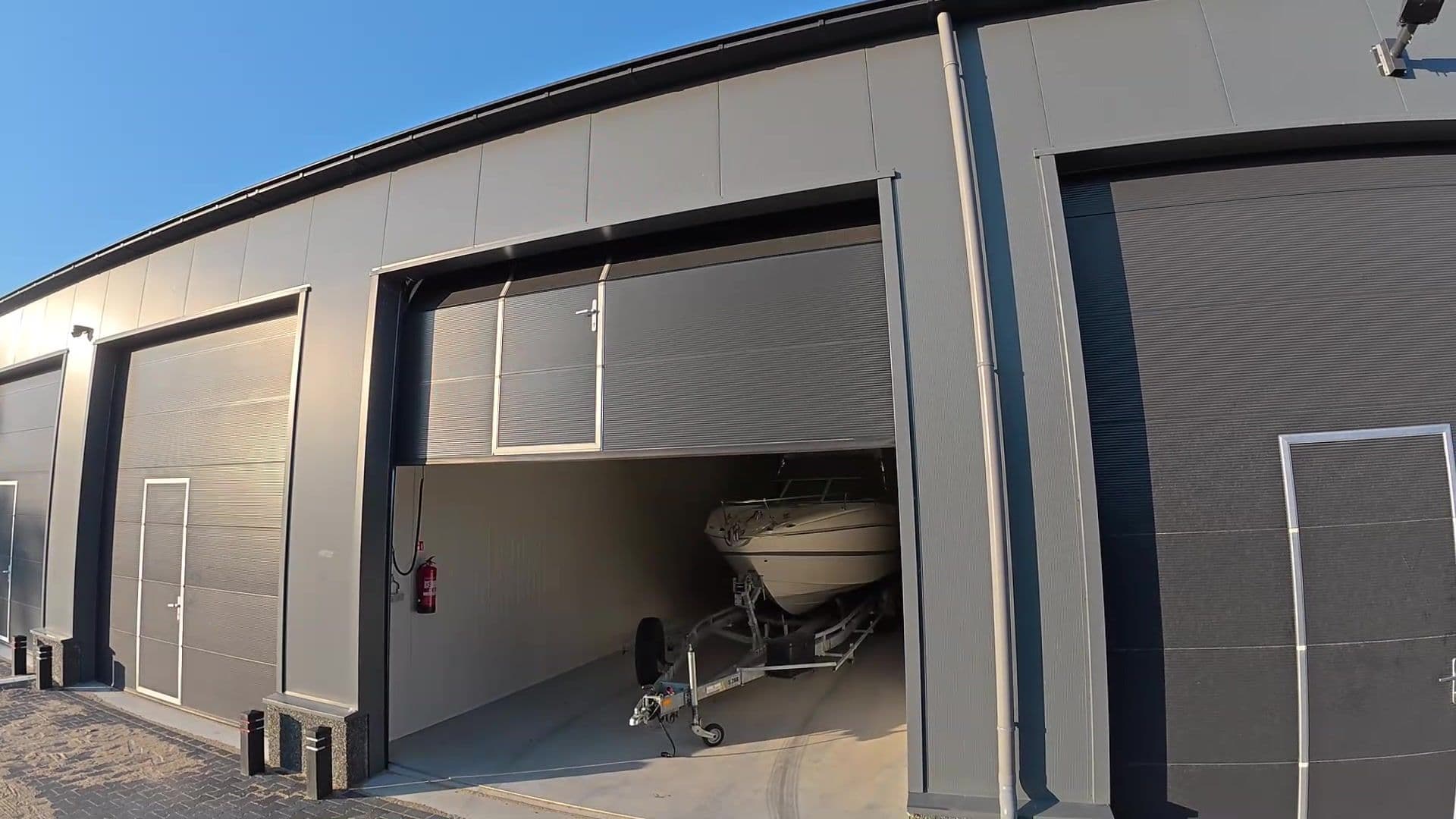Een boot op een trailer in een unit met geopende overheaddeur