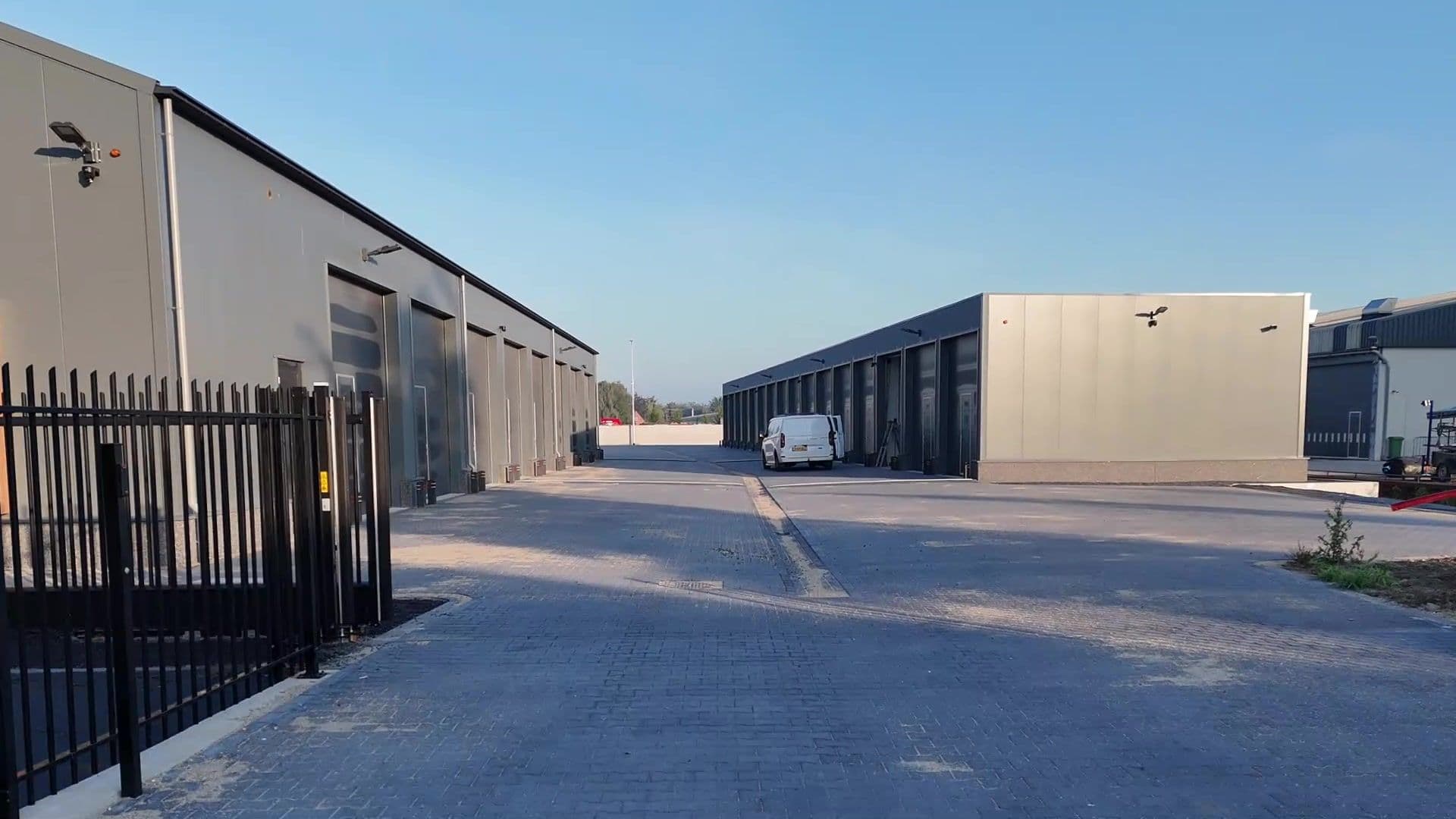 Het terrein in Velddriel met een hek, een brede verharde weg en rijen units met overheaddeuren